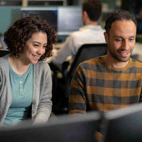 Twee collega's die gezamenlijk aan een bureau voor een laptop zitten